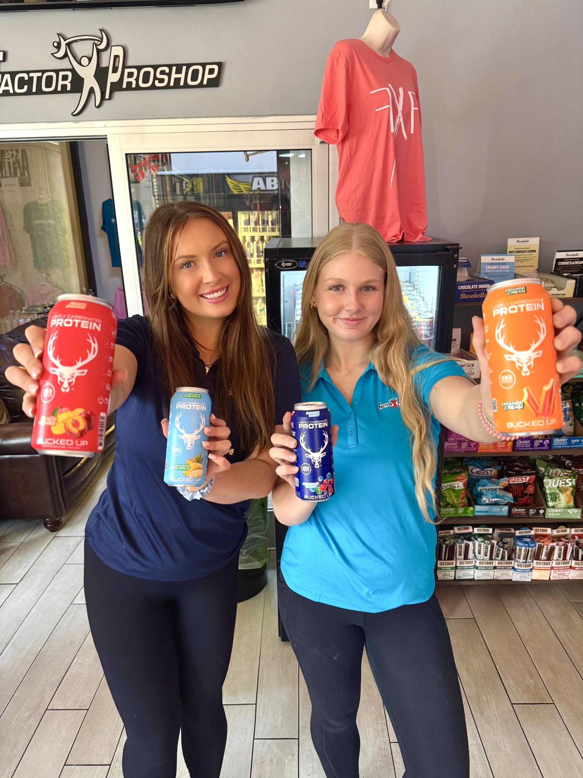 Two girls holding cans of protein drinks