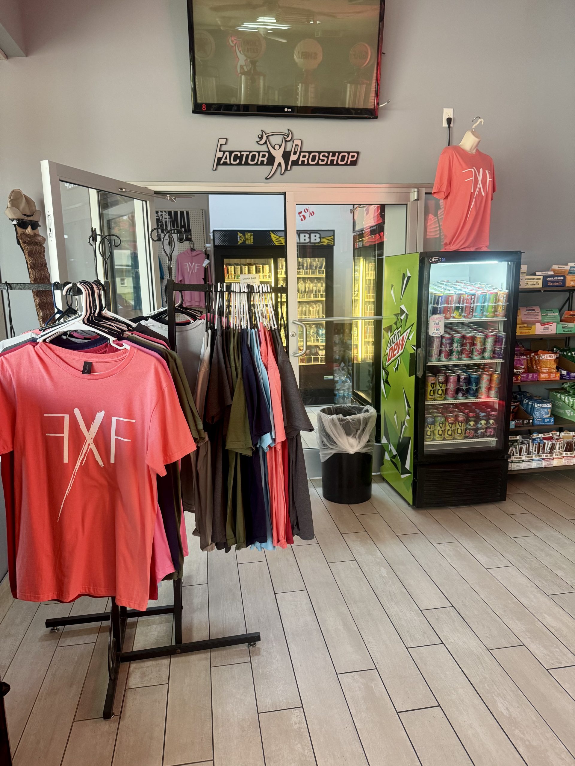 Photo of the shop floor. Racks of clothing, fridges stocked with drinks, and shelves with items.